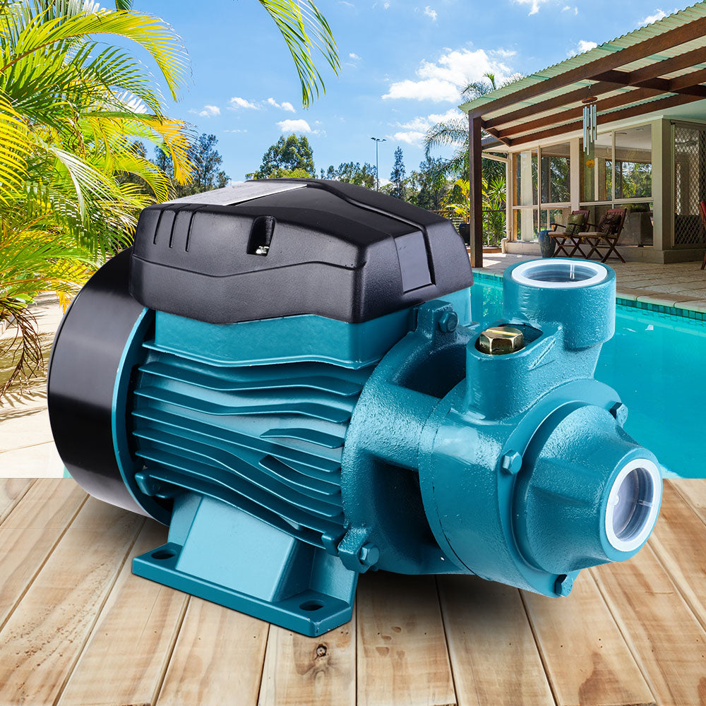 Teal and black pump on a wooden deck with a pool and outdoor furniture in the background