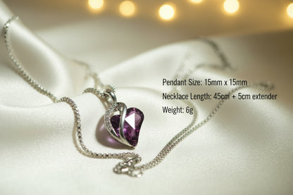 Heart-shaped purple gemstone pendant on a chain against a light green background