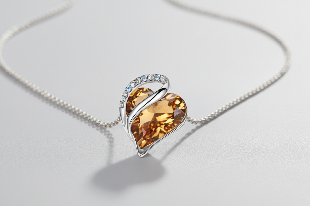 Heart-shaped crystal pendant on a chain against a light gray background