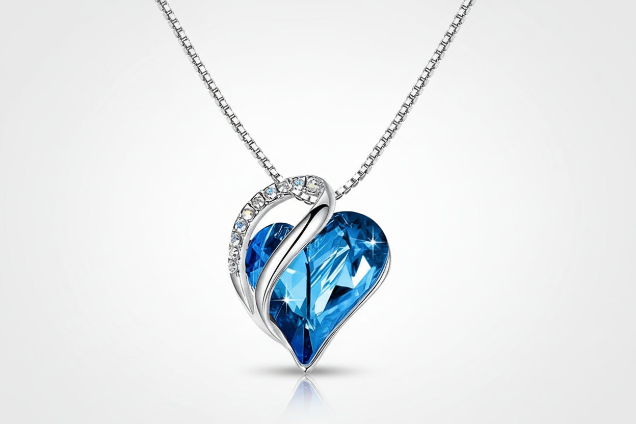 Heart-shaped blue crystal pendant on a silver chain against a white background